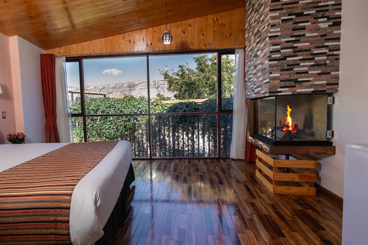 Een slaapkamer met een groot bed, een open haard en een balkon met uitzicht.