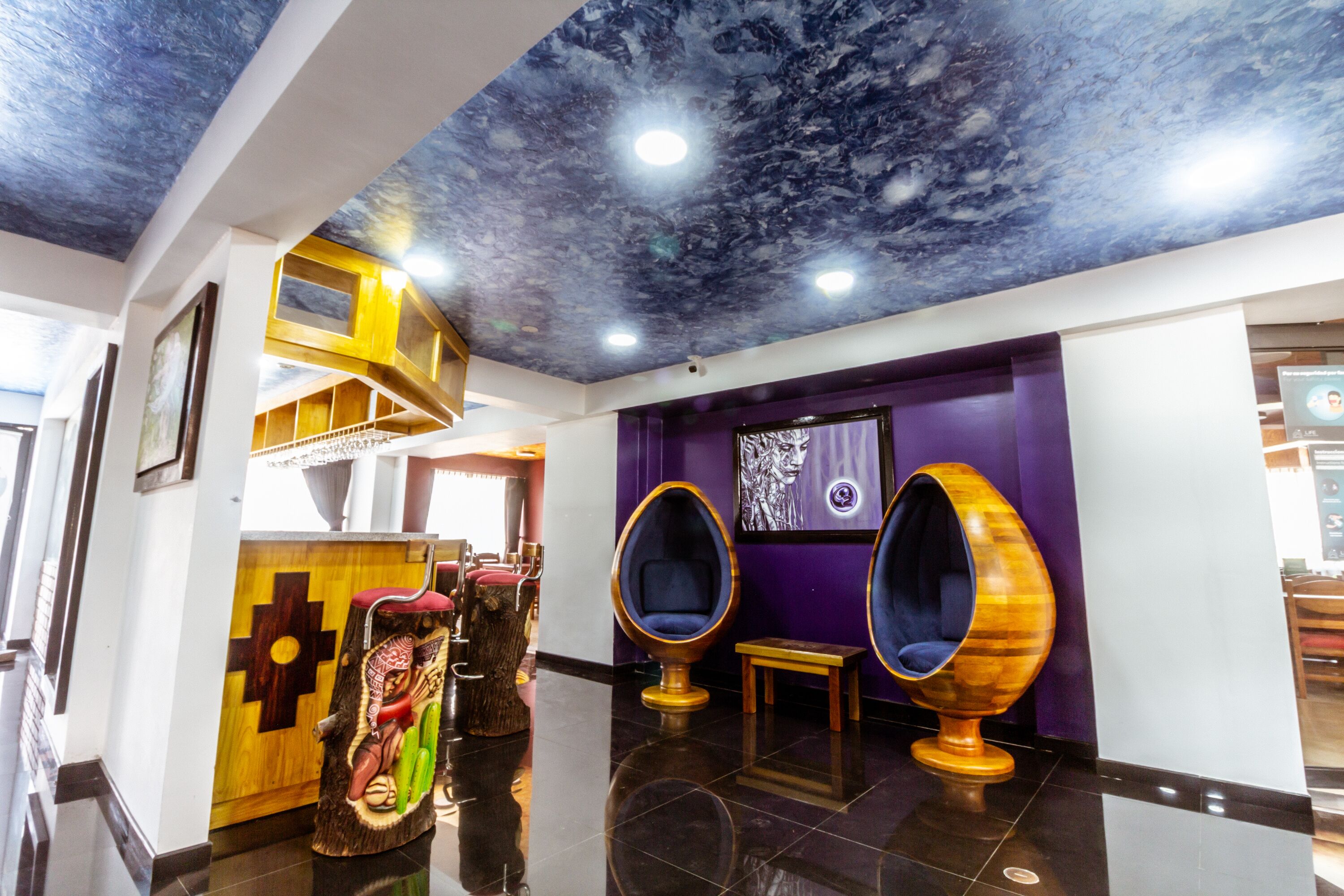 A lobby with a high ceiling, a reception desk, and two unique egg-shaped seating areas.