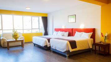 A hotel room with two beds, a sofa, a small table, and a window with curtains.