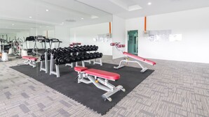 Une salle de sport moderne équipée de tapis de course, d’haltères et de bancs de musculation.