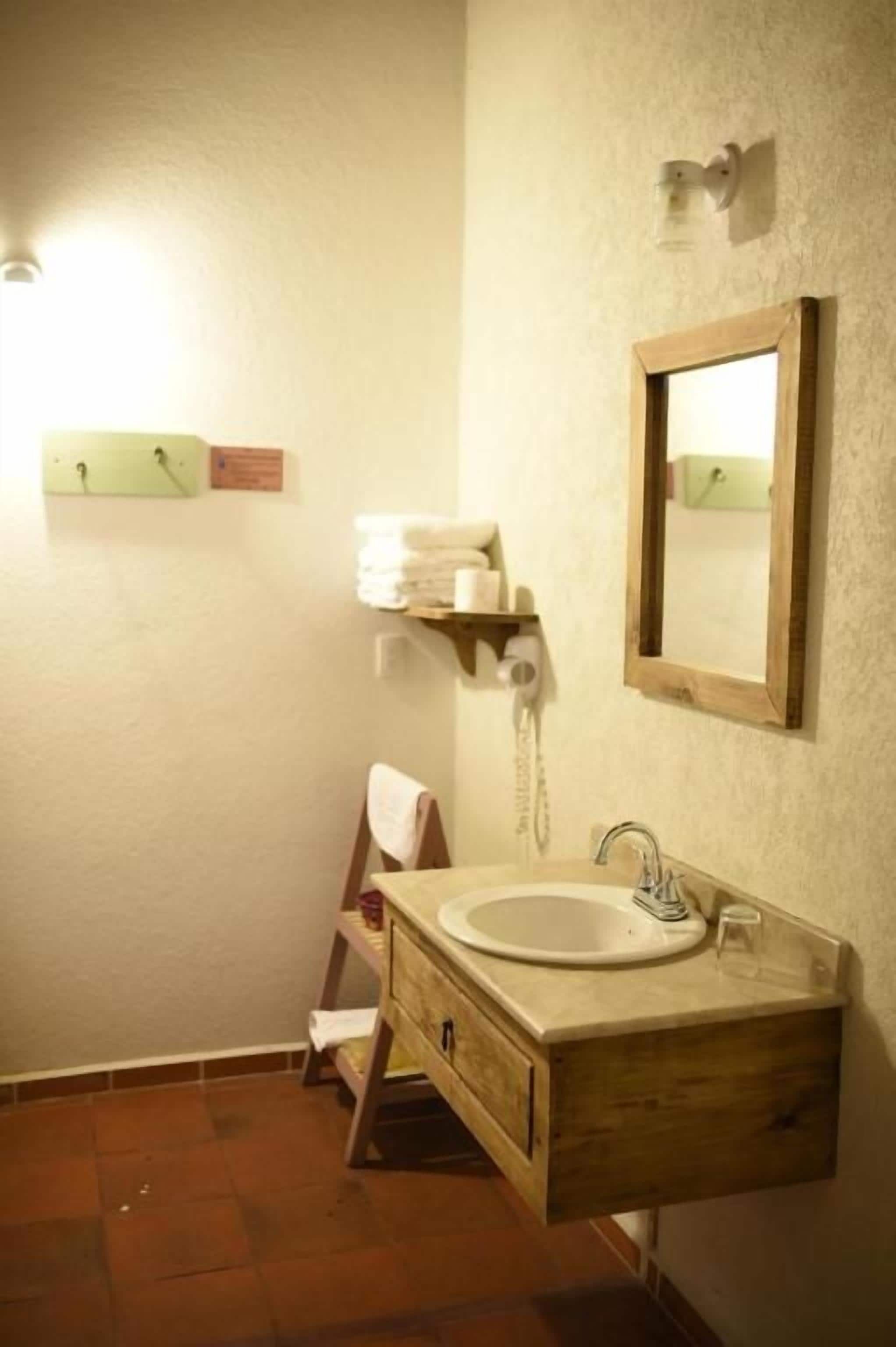 Une salle de bain avec un meuble-lavabo en bois, un évier et un miroir.