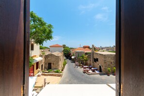 A view of a narrow street with traditional stone buildings, a clear blue sky, and a few potted plants. - Cleomenes Studios (Rhodes)