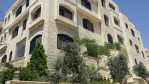 A multi-story building with a stone facade, multiple windows, and a balcony. - Sports City Jewel (Amman)