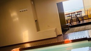 An indoor swimming pool with a clear view of the ocean through a large window. - Mision Costa (La Oliva)
