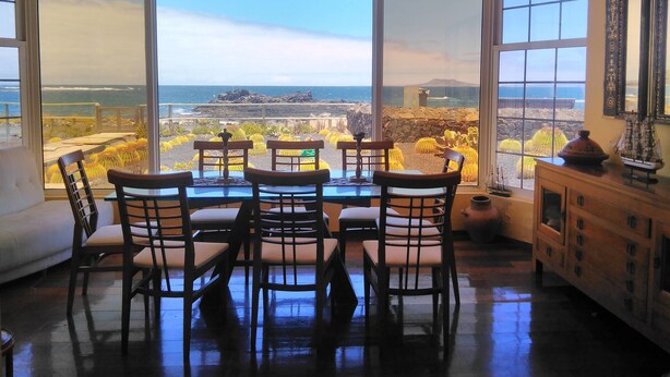 A dining area with a view of the ocean through large windows. - Mision Costa (La Oliva)