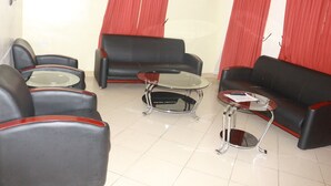 A lobby with black leather sofas, a glass coffee table, and a small round table. - Ann's Haven Hotel & Suites (Uyo)