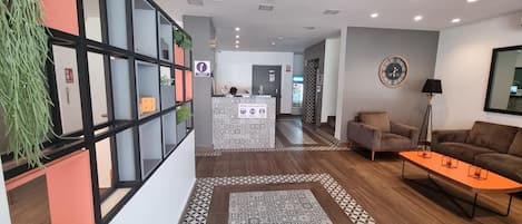 Un moderno vestíbulo de hotel con mostrador de recepción, zona de estar y suelo estampado.