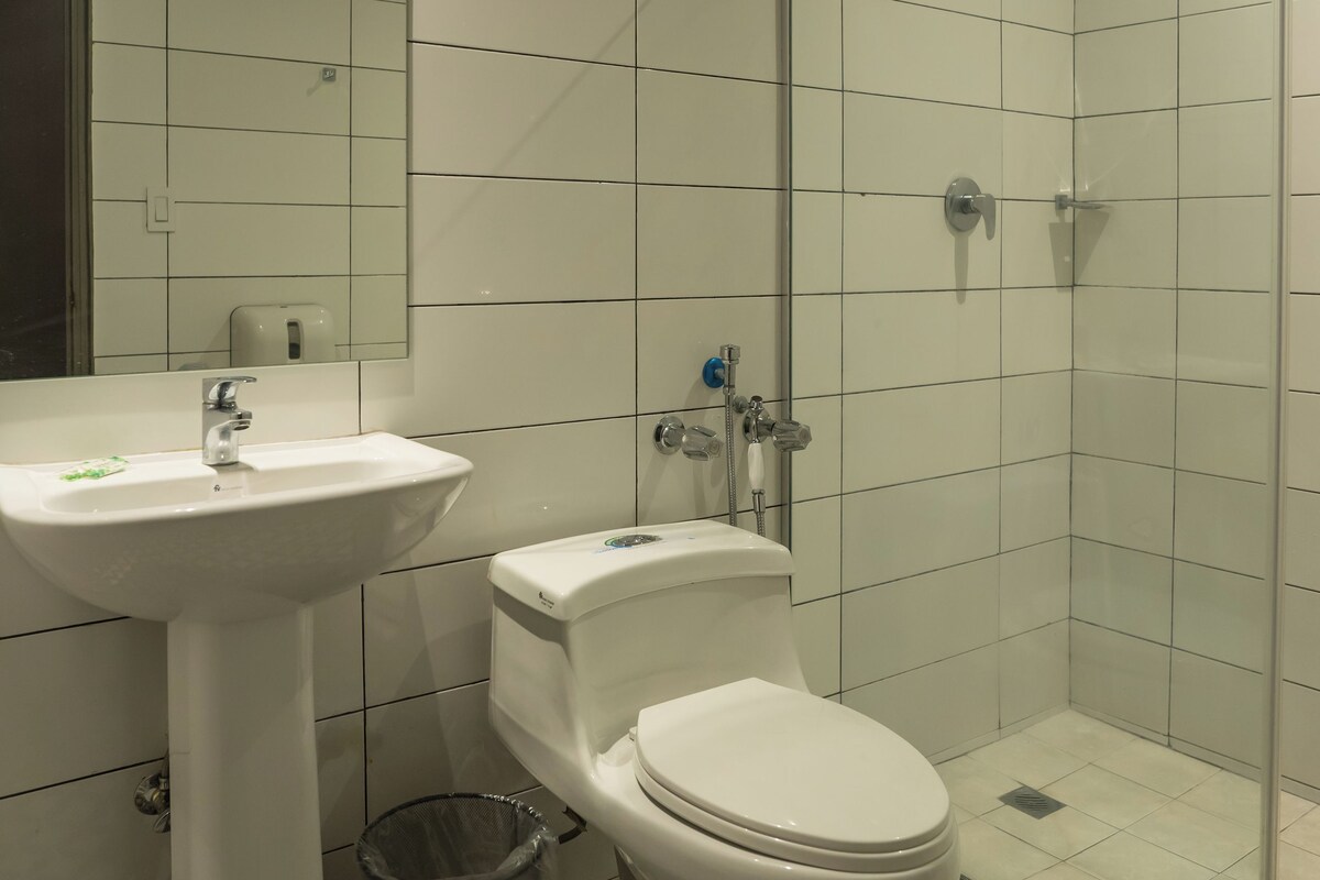 A bathroom with a white sink, toilet, and glass-enclosed shower.