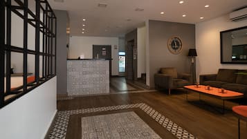 Un hall d’entrée moderne avec un comptoir de réception, des carreaux de sol à motifs, un canapé, une table basse et une horloge murale.