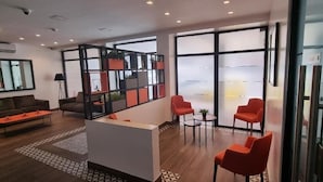 Un moderno vestíbulo de hotel con mostrador de recepción, zona de estar y grandes ventanales.