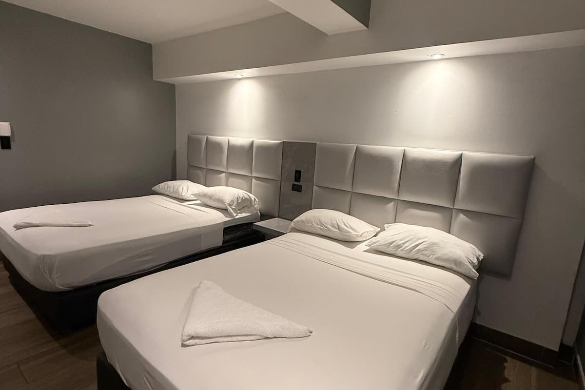 A hotel room with two beds, a modern design, and a neutral color scheme.