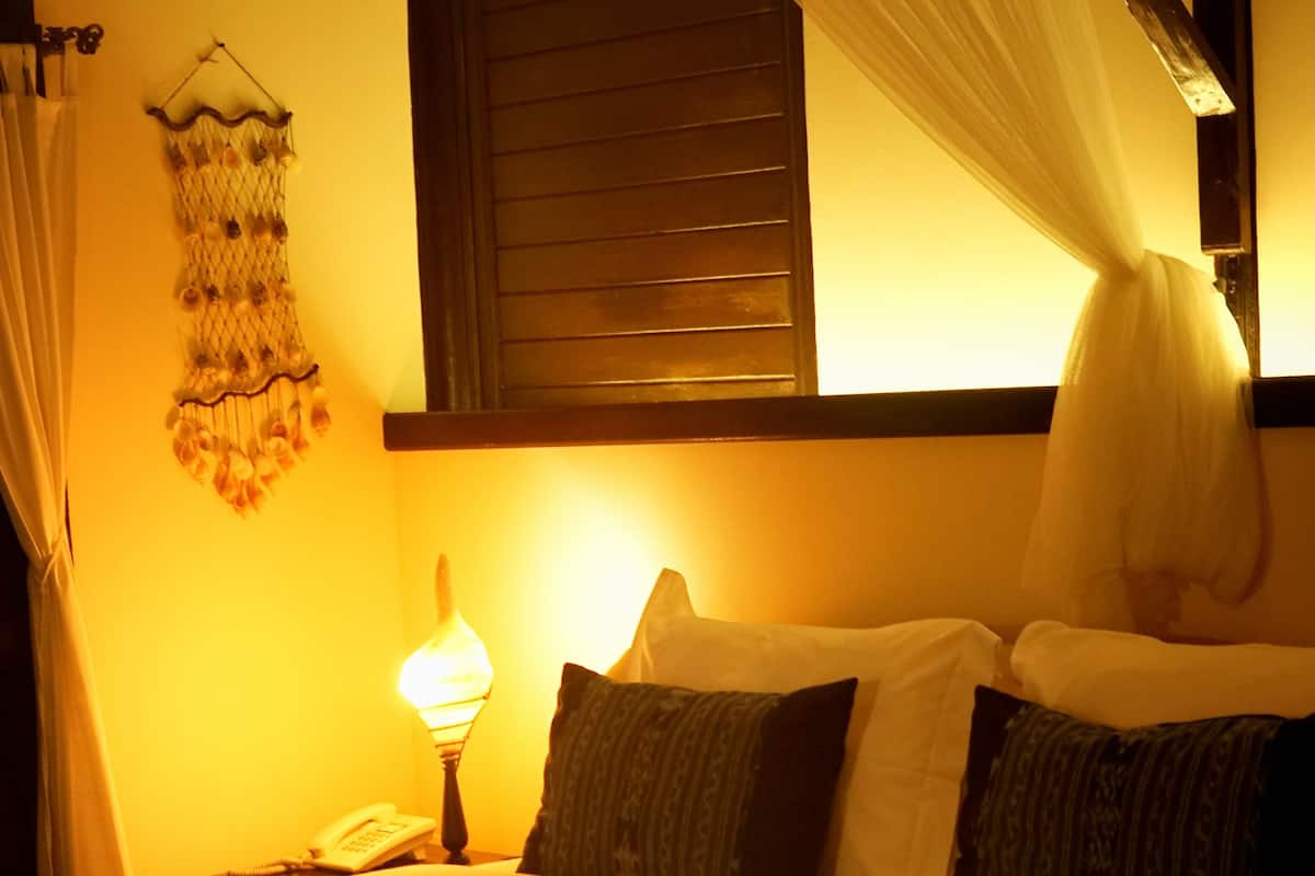A bed with a canopy, a bedside lamp, and a decorative wall hanging.