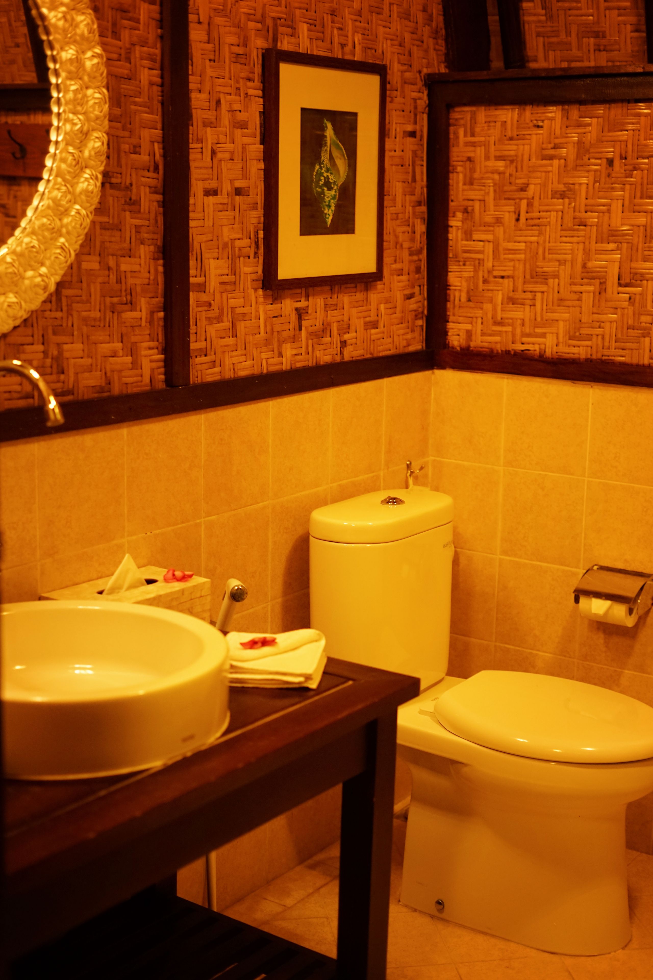 Un bany amb un disseny de paret trenada, un lavabo, una tassa i una fotografia encadrada a la paret.