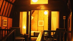 A warmly lit room with a bed, a wooden chair, and a small table. - Samawa Seaside Resort (Sumbawa Besar)