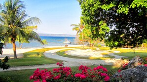 A landscaped garden with a pathway leading to a beach. - Samawa Seaside Resort (Sumbawa Besar)
