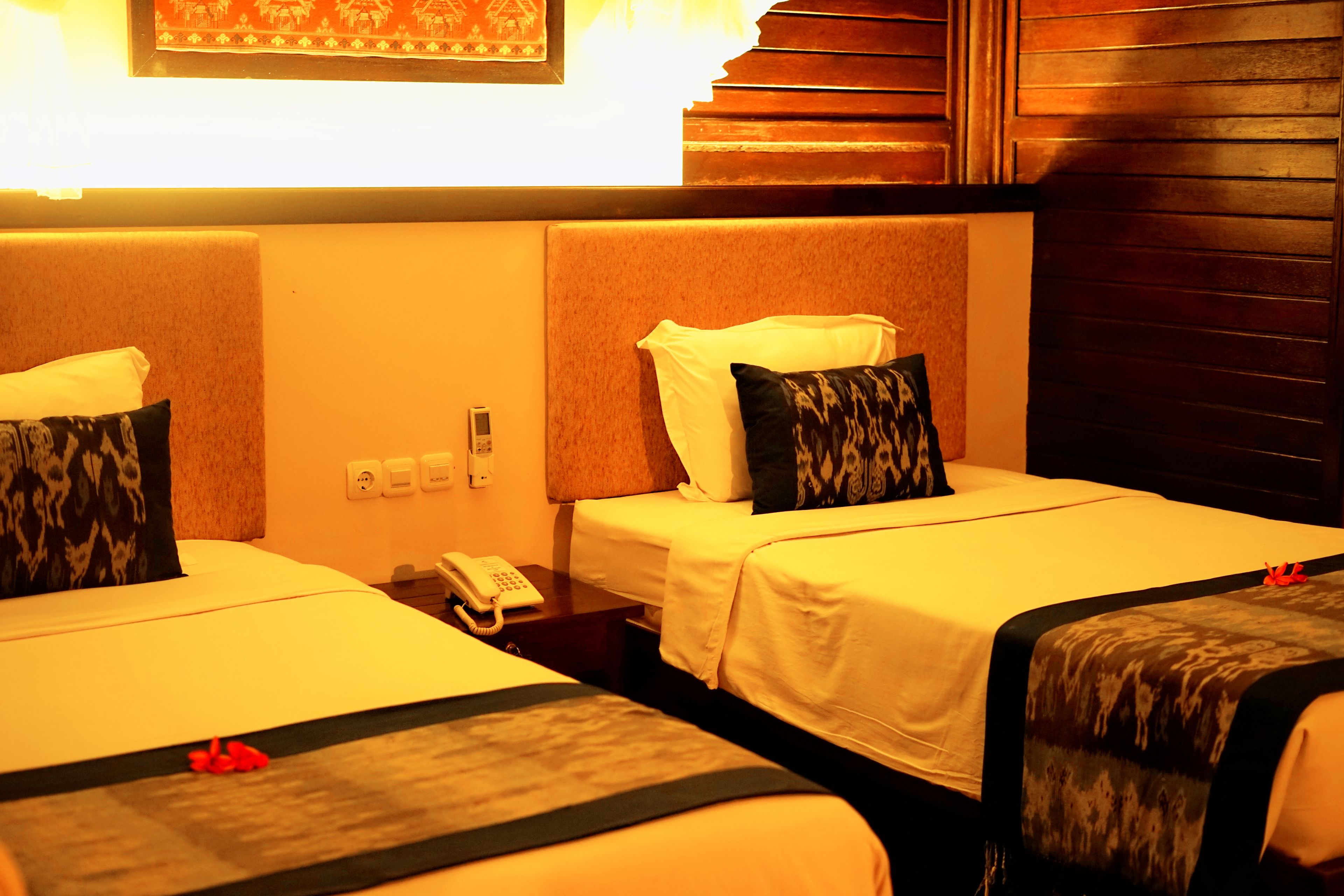 A hotel room with two single beds, each with a pillow and a bedside table.