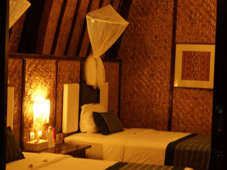A room with two beds, a canopy bed, a wall-mounted lamp, and a framed picture.