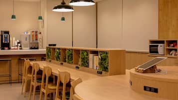 A modern interior with a wooden counter, chairs, pendant lights, and a digital tablet.