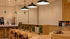 A modern cafe with wooden furniture, pendant lighting, and a digital tablet on a wooden counter.