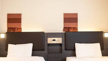 A hotel room with two beds, a control panel, and wall-mounted lamps.