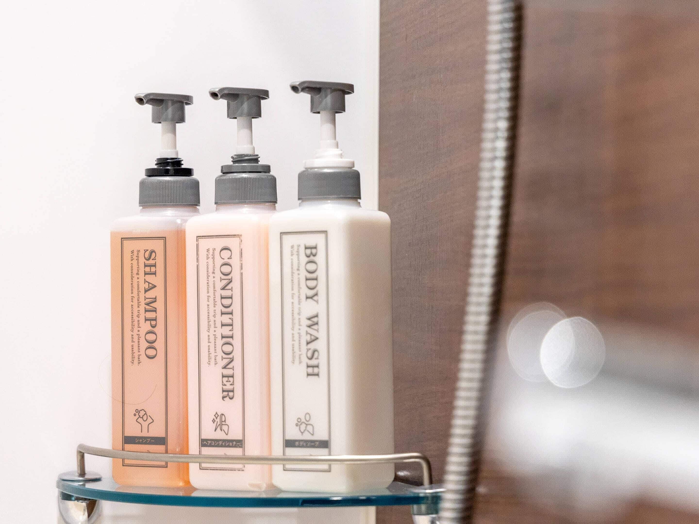 Drie flessen shampoo, conditioner en douchegel op een badkamerschaar.