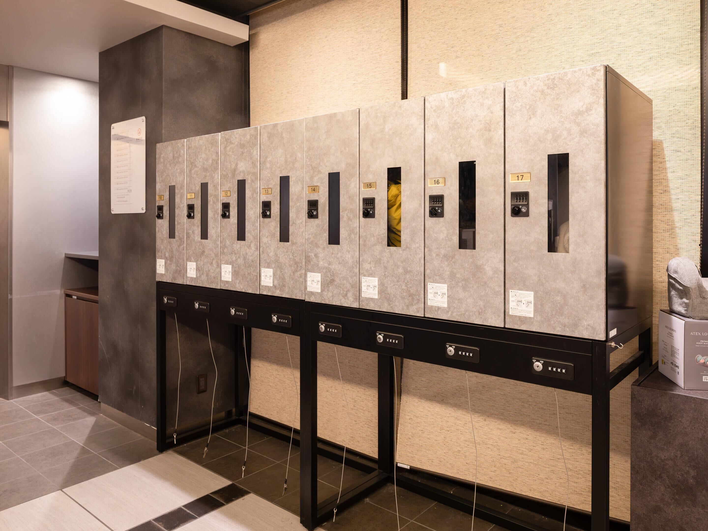 A row of hotel rooms with individual door numbers and a control panel at the end.