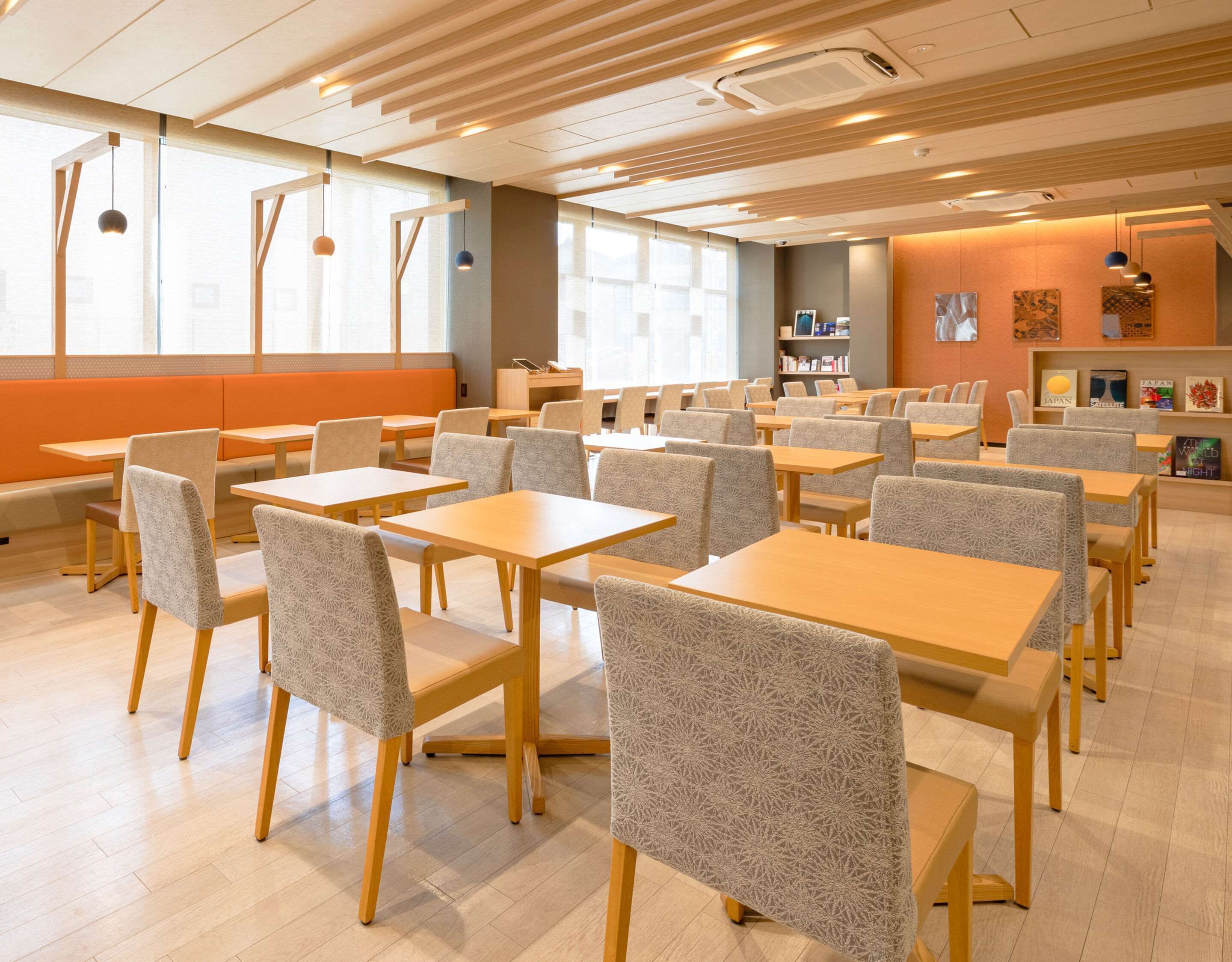 A spacious dining area with multiple tables and chairs, a bookshelf, and a seating area with a bench.
