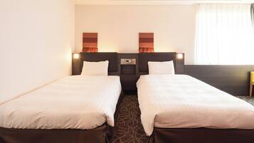 A hotel room with two single beds, a control panel, and a window with curtains.