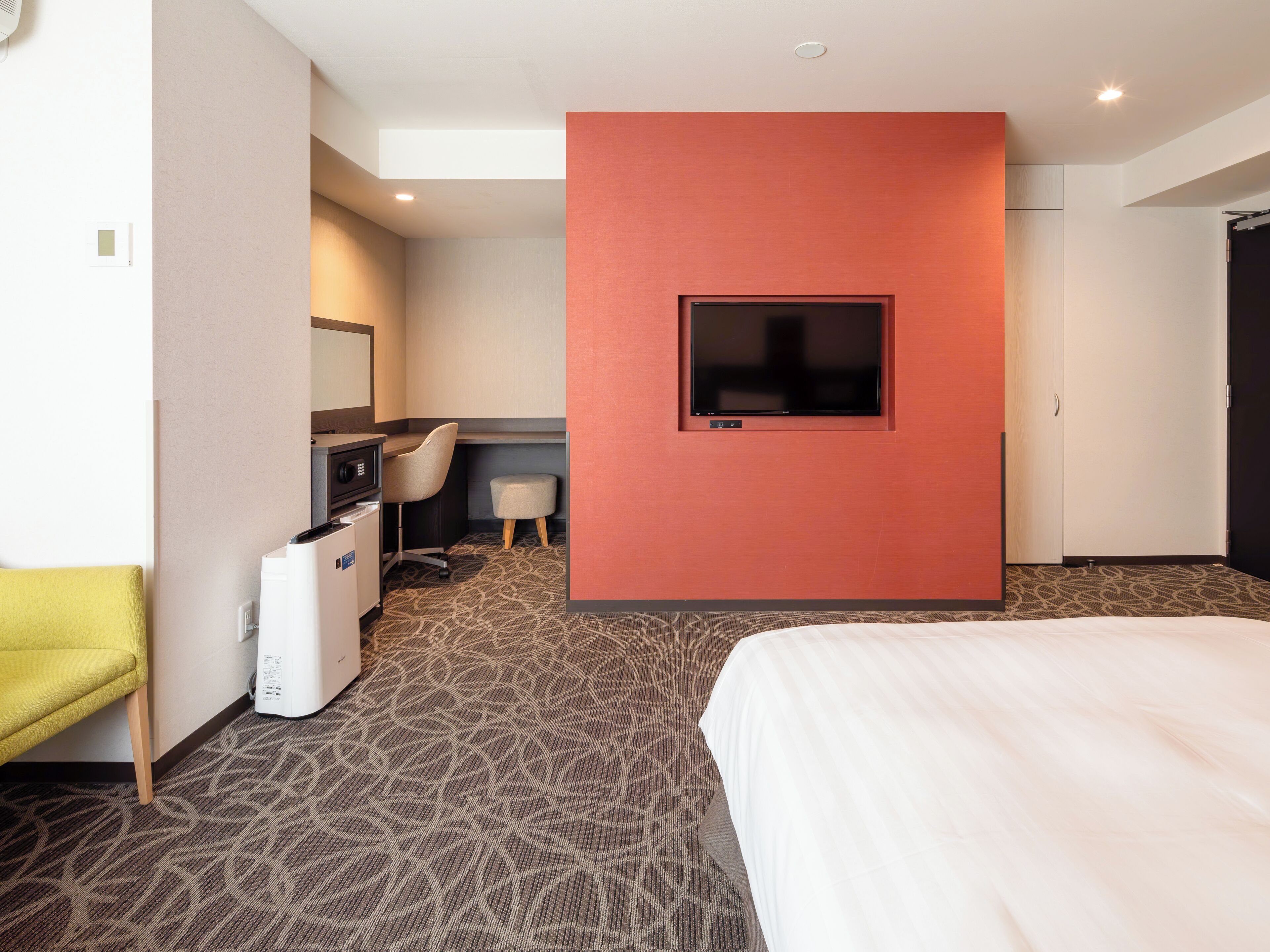 Habitación de hotel con cama, escritorio, silla, televisor y minibar.