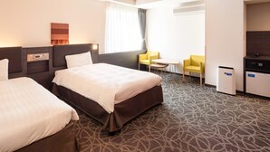 Ein Hotelzimmer mit zwei Betten, einem kleinen Tisch, zwei Stühlen, einem Fernseher und einer Klimaanlage.