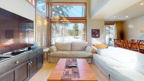 A modern interior with a sofa, a dining table, and a TV. - Snowcreek Resort Vacation Rental 719 (Mammoth Lakes)