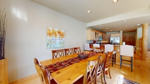 A dining area with a wooden table, chairs, and a painting on the wall.