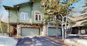 A two-story house with a stone facade, a garage, and a driveway.