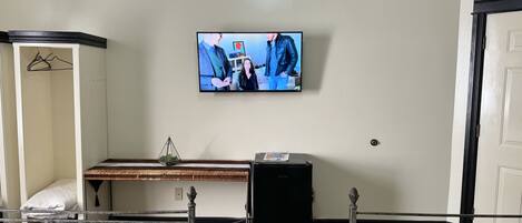 A hotel room with a bed, a desk, a television, and a wardrobe.