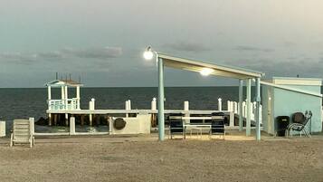 A pier with a covered seating area, a small building, and a view of the water.