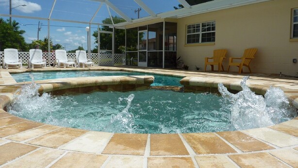 A covered outdoor swimming pool with a hot tub, surrounded by lounge chairs and a patio area. - Sun, beach, and great savings –discover amazing discounts on dream destinations! (Cape Coral)