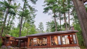 Een vakantiehuisje van hout met een stenen fundering, grote ramen en een overdekte veranda.