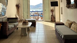 A spacious living room with a view of the sea, a large window, and a flat-screen TV. - Paros Dream House #Naoussa Parodise (Naousa)