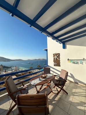 A terrace with a view of the sea, featuring a table and chairs, a starfish decoration, and a metal rack with colorful items.
