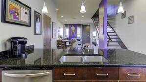 A modern kitchen with granite countertops, stainless steel appliances, and pendant lighting.
