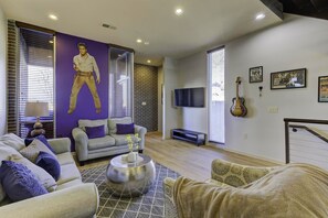 A living room with a large Elvis Presley statue, a grey sofa, a patterned rug, and a TV on the wall. - 2 bedroom / 2.5 bath Memphis Condo - Prime Downtown Location! Newly Renovated (Memphis)