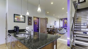 A modern kitchen with granite countertops, stainless steel appliances, and pendant lighting.