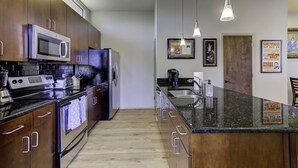 A modern kitchen with stainless steel appliances, wooden cabinets, and a granite countertop.