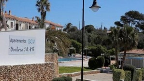 A sign for 'Apartamentos GVA' with a pool and landscaped garden in the background. - Binibeca Mar (Sant Lluis)