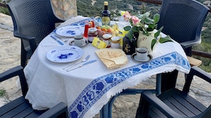 A table set with plates, cutlery, and food items on a terrace overlooking the sea. - Villa 2 apartments ,1 or 2 families, panoramic sea view & sunset (Sinnai)