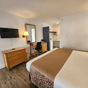 A hotel room with a bed, a desk with a chair, a television, a mirror, a dresser, and a microwave. - Skylark Shores Resort (Lakeport)