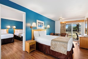 A hotel room with two beds, a desk, a chair, and a view of the outdoors.