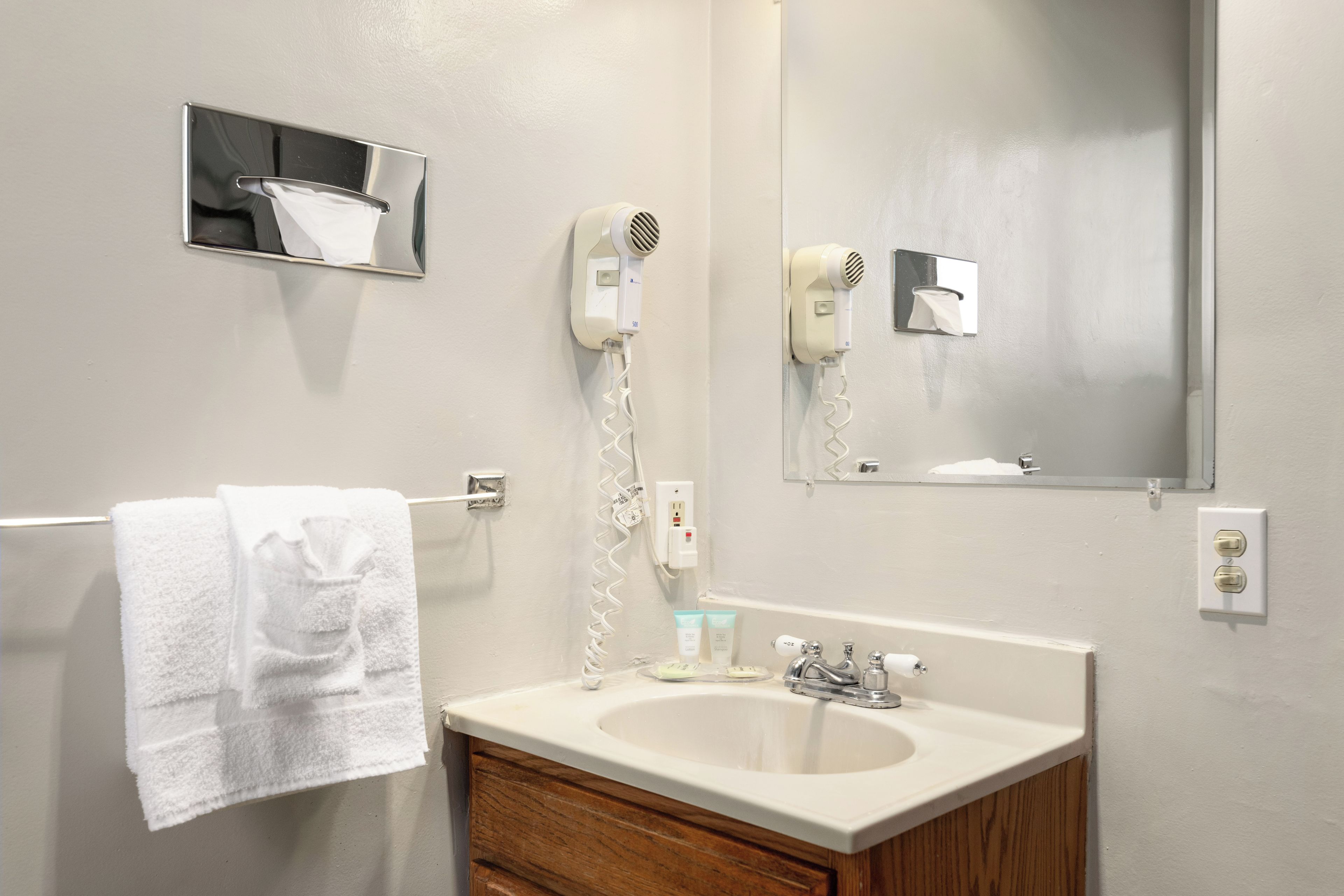 A bathroom with a sink, mirror, towel rack, and hair dryer.