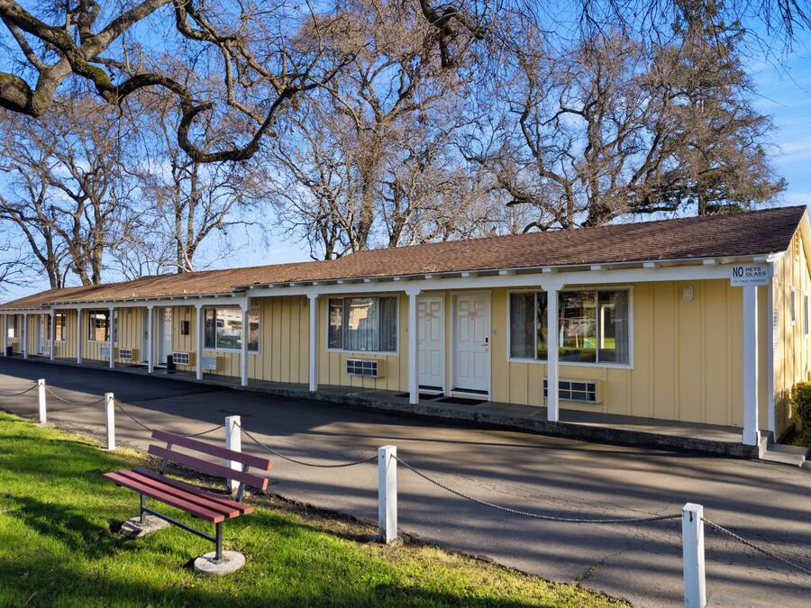 A row of yellow motel rooms with white trim and a 'No Pets Allowed' sign.