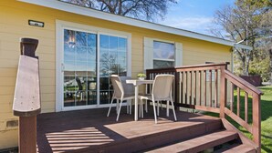 A wooden deck with a table and chairs, a wooden staircase, and a sliding glass door. - Skylark Shores Resort (Lakeport)